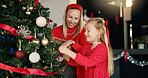 Christmas, mother and daughter with tree for decoration for festive holiday, tradition or help. Girl child, excited woman and ornament in family home for celebration, happiness and ball for bonding