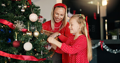 Buy stock photo Christmas, mother and daughter with tree for decoration for festive holiday, tradition or help. Girl child, excited woman and ornament in family home for celebration, happiness and ball for bonding