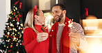Happy couple, celebration and christmas with sparklers in home for festive holiday or weekend. Man, woman or lovers with smile or fireworks for December party, new year or bonding together in house