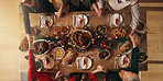 Holding hands, praying and people in home, dinner or gratitude for food on Christmas or celebration. Above, faith and prayer for feast on holiday, group and family in house for thanksgiving and night