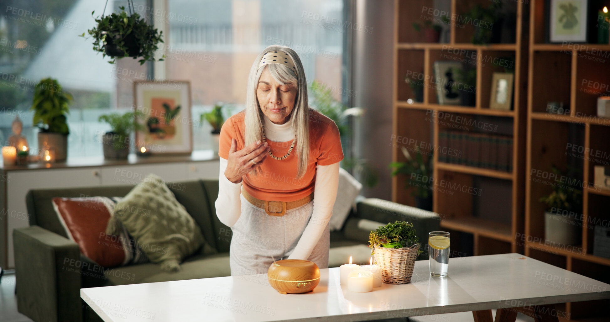 Buy stock photo Diffuser, aroma and woman with candles in home for peaceful ambiance, aromatherapy and zen. Tranquility, mature person and fragrance in living room for holistic healing, stress relief and self care