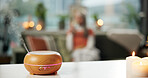Aromatherapy, relax and peace with diffuser in home for wellness, bokeh and zen candle. Stress relief, essential oils and smoke with person in living room of apartment for humidifier and self care