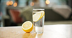 Counter, glass and water with lemon in kitchen for detox, antioxidant or vitamin c for wellness. Diet, weight loss and citrus fruit in liquid, drink and mineral for digestion, gut health or nutrition