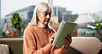 Senior woman, tablet and relax on sofa in living room for ebook, article or web subscription service in home. Person, tech and scroll for movie streaming, app or social network in lounge at house