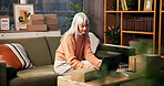 Laptop, mature woman and living room for order, logistics and check online for ecommerce and remote work. Package, technology and freelance entrepreneur in home for stock, shipping or quality control