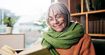 Senior woman, smile and reading book on sofa with story, poetry or novel in living room at house. Person, happy and relax with literature, knowledge or info on couch in lounge at retirement home