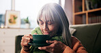Mature, happy woman and smell with coffee in home for morning beverage or caffeine drink. Calm, female person and relax with mug or cup for fresh start, aroma or scent in living room or house