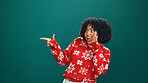 Christmas, pointing and whisper with woman in studio for holiday season, celebration and promotion. Festive deals, xmas event and announcement with person on green background space for mockup