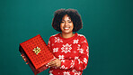 Christmas gift, portrait and black woman in studio for tradition, prize or giveaway on holiday. Excited, celebration and African female person with xmas present for festive season by green background
