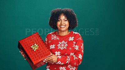Buy stock photo Christmas gift, portrait and black woman in studio for tradition, prize or giveaway on holiday. Excited, celebration and African female person with xmas present for festive season by green background