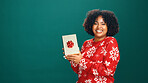 Christmas present, portrait and black woman in studio for tradition, prize or giveaway on holiday. Excited, mockup space and African person with xmas gift for festive season by green background.