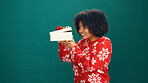 Gift box, happy and black woman in studio for christmas with curiosity for tradition, prize or giveaway. Smile, mockup space and person peeking at xmas present for festive season by green background.
