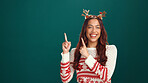 Christmas, pointing and smile with portrait of woman in studio for holiday season, celebration and promotion. Festive deals, xmas and announcement with person on green background space for mockup