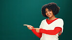 Christmas, woman and pointing to space in studio for advertising, marketing or mockup. Portrait, smile and African person with promotion offer, xmas discount and festive sale on green background