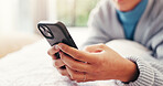 Hands, phone and texting on bed, home and contact with web chat, relax and check notification in morning. Person, smartphone and scroll on mobile app, social media and post in bedroom at apartment