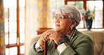 Walking stick, thinking and senior woman in home with nostalgia, retirement or remember memory. Ideas, wood cane and elderly female person with a disability on sofa with daydreaming in house.