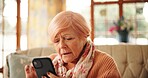 Senior woman, reading and phone at house for message, communication and social media. Elderly person, confused and mobile with online games, browsing website and problem solving of crossword activity