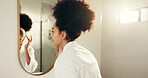 Woman, mirror and skincare with facial cream for morning routine in bathroom, moisturizing and cosmetics. African person, reflection and daily skin care for dermatology, sunscreen and beauty in home
