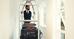 Hotel, porter and luggage cart in hallway for bags delivery, welcome service or guest arrival. Concierge, hospitality or man push trolley at luxury resort for bellboy assistance or transport suitcase
