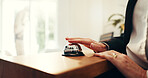 Person, hands and reception with service bell for request assistance or help in hotel. Closeup, client or customer with alert on front desk for response, question or accommodation in luxury resort