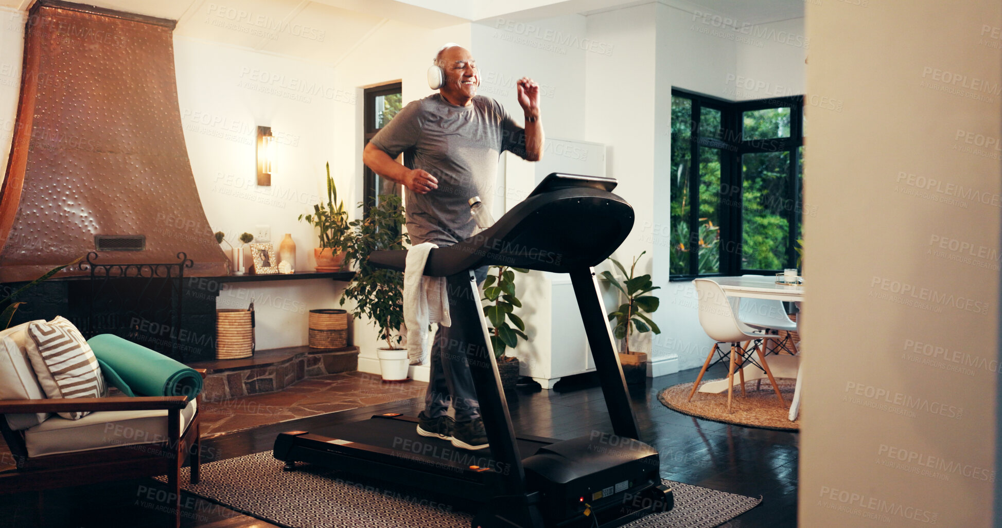 Buy stock photo Senior, happy man and running with headphones on treadmill in home for fitness, workout or exercise. Active, elderly runner or male person on step machine for cardio training or lose weight in house