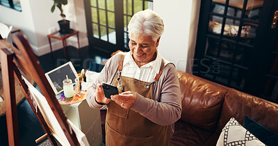 Buy stock photo Senior woman, painter and phone with canvas, smile and texting in home studio, chat and contact on web. Elderly person, artist and smartphone with social media, mobile app and above in retirement