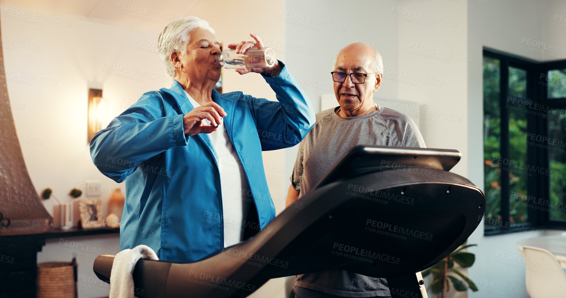 Buy stock photo Senior woman, treadmill and drinking water in home for training, rest or hydration in retirement. Elderly man, couple and partner with bottle, gym equipment and exercise machine with support at house