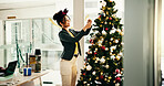 Business woman, baubles and Christmas tree at office with ornament, happy and festive bow for event. Person, smile and hanging ball with xmas celebration, lights or interior design at creative agency