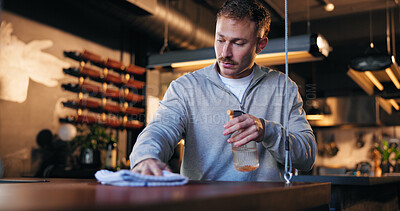 Buy stock photo Man, bartender and cleaning with cloth for hygiene, dust and service for drinks at restaurant. Person, owner and check for dirt with spray bottle, shine and cafe with inspection at small business