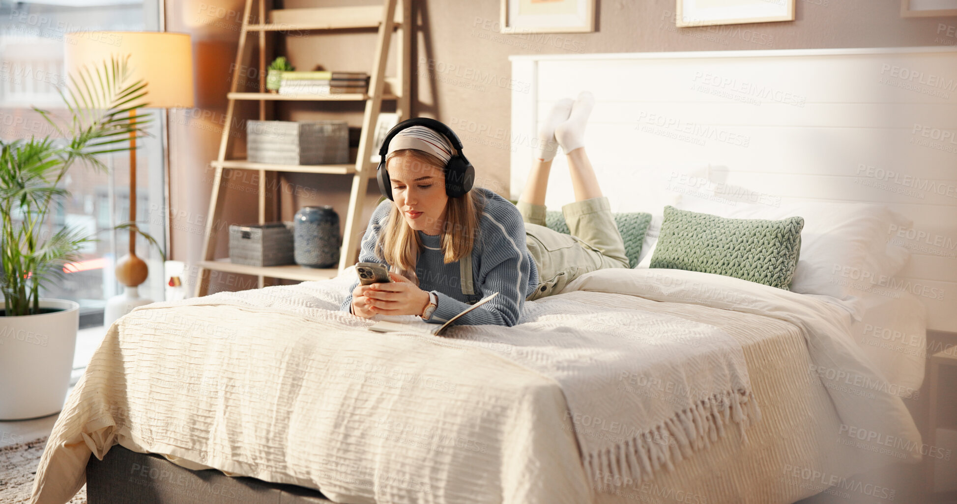 Buy stock photo Notebook, bed and woman with headphones in home to relax, writing in journal and social media. Bedroom, apartment and person with phone listening to audio, radio and streaming music for inspiration