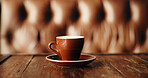 Caffeine, cup and wooden table in coffee shop booth for fresh beverage hospitality or service. Background, drink and interior with mug on surface in empty restaurant for small business startup