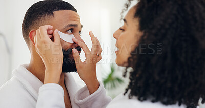 Buy stock photo Couple, eye patches and help in bathroom for facial treatment, vitamin C or collagen in home. Man, woman or assistance with cosmetics, product or mask for beauty, health or wellness together in house