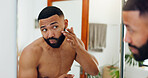Skincare, man and mirror in bathroom for inspection, check acne and beard growth in home. Person, reflection and touch face in apartment for grooming, dermatology and topless in morning routine
