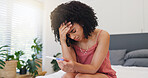 Frustrated woman, headache or stress with pregnancy test in bed for mistake or abortion in home. Upset, female person or migraine with anxiety, maternity stick or positive results in bedroom or house