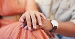 Closeup, couple and holding hands in home with care, marriage and connection with love in lounge. People, partnership and support with loyalty, touch or relax together in living room at apartment