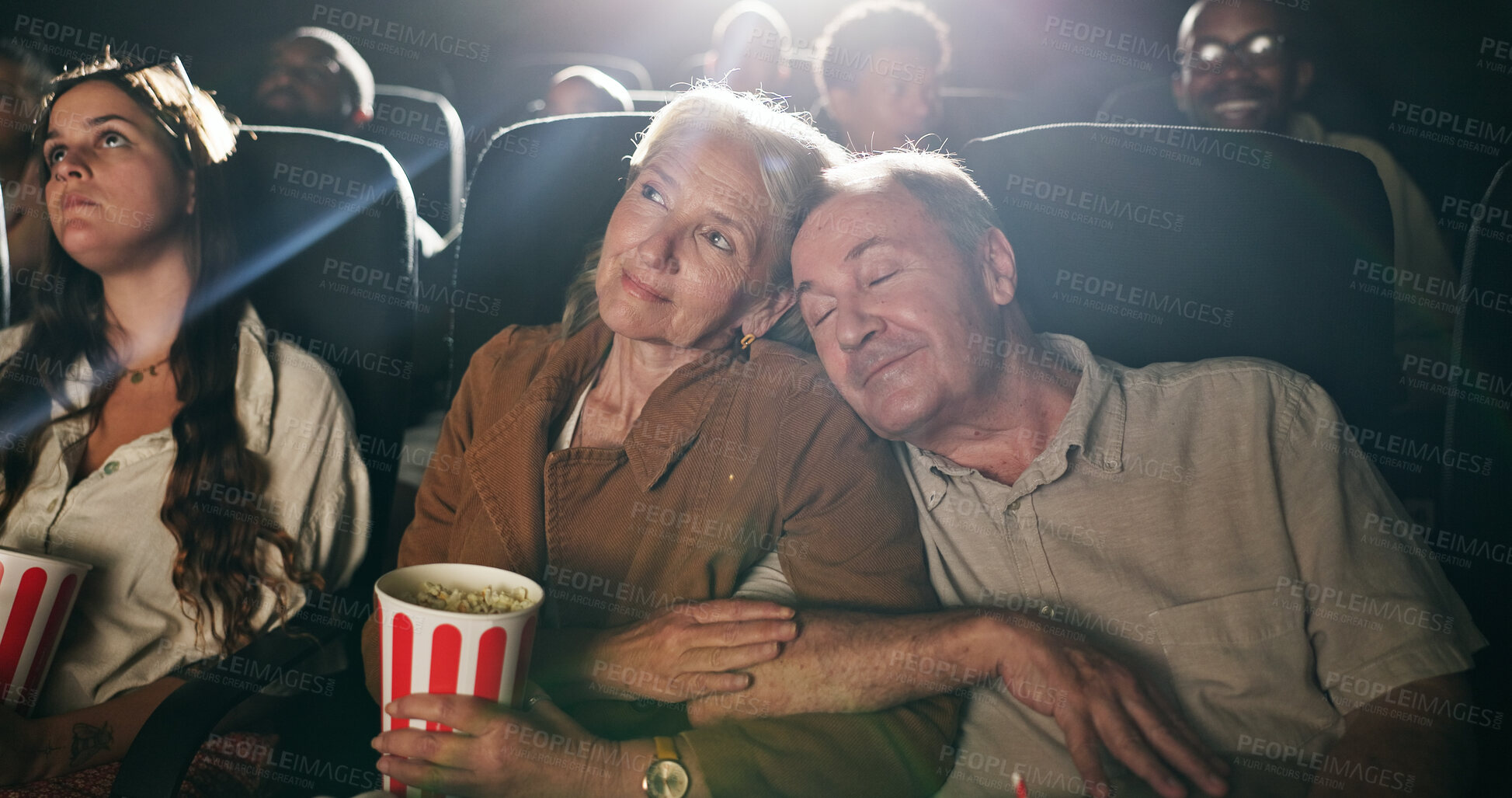Buy stock photo Senior couple, popcorn and sleep at movie theater with smile in crowd, bonding and show on date. Elderly people, relax together and love with fast food, snack and care with film screening at cinema