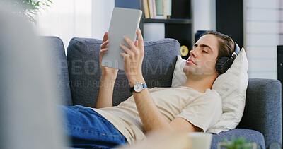 Buy stock photo Man, headphones and tablet on couch for relax, streaming media and entertainment app. Chill, music platform or male person on technology in home for audio book, podcast or blog on living room sofa