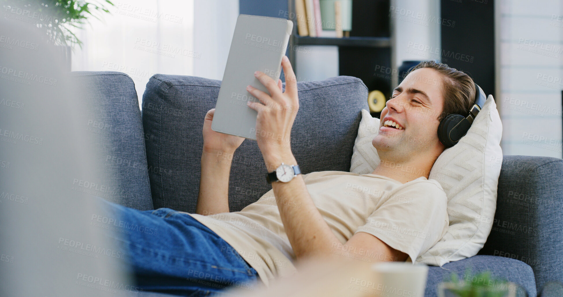 Buy stock photo Happy man, headphones and tablet on sofa for relax, streaming media and entertainment app. Chill, music platform or male person on technology in home for audio book, podcast or comfort in living room