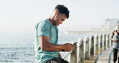 Buy stock photo Happy man, fitness and break with phone for sport app, social media or connection on promenade. Active, male person or rest with mobile smartphone or earphones for workout schedule on ocean coast