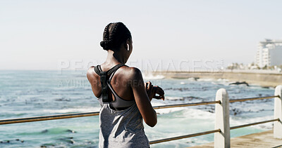 Buy stock photo Black woman, back or fitness with watch on ocean coast for sport app, time or workout schedule. Active, female person or runner checking wristwatch for heart rate or step counter on outdoor promenade