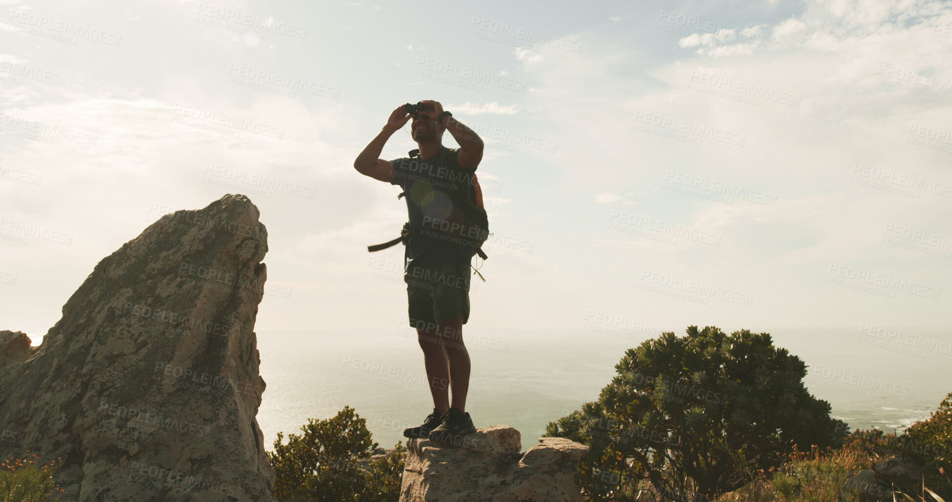 Buy stock photo Man, binoculars and hiking on mountain, sky and smile for sightseeing, birdwatching or adventure. Person, view and space with landmark, outdoor and happy with trekking on trail in summer in Spain