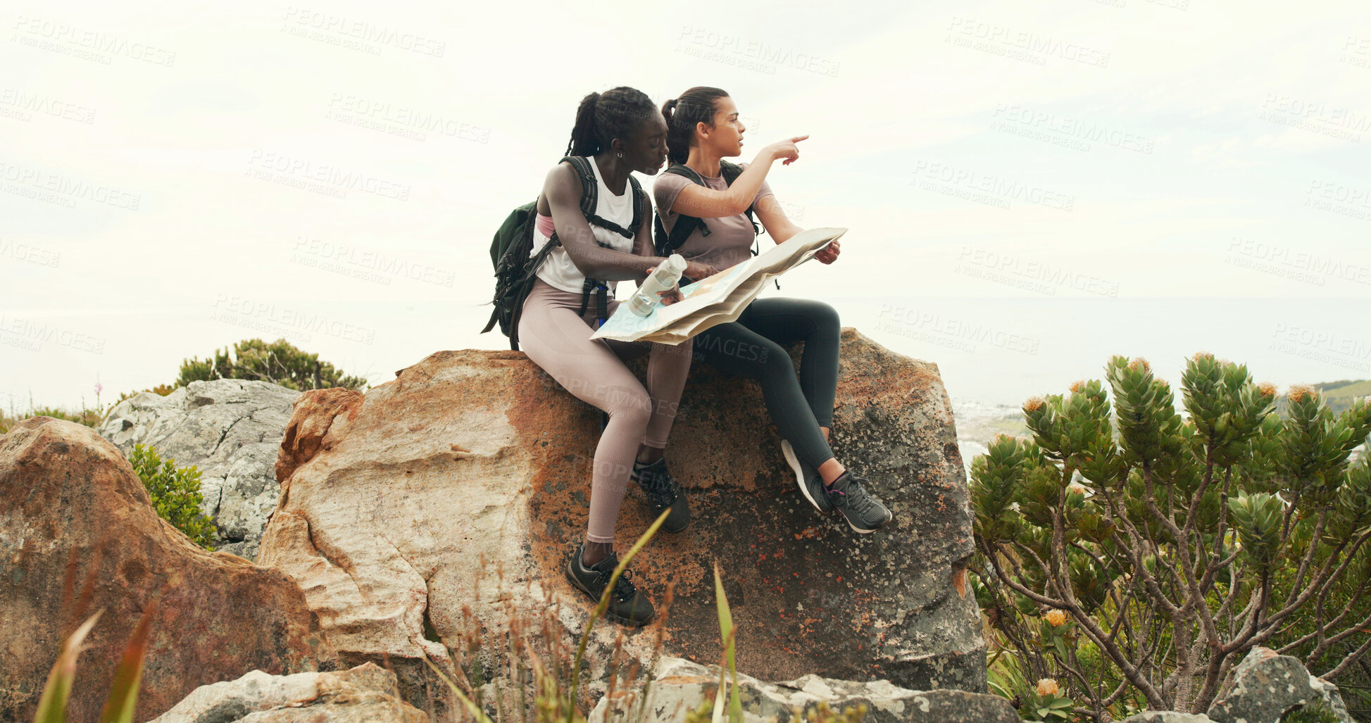 Buy stock photo Women, map and hiking with point on mountain, talk and search for direction on trail for tourism. Girl, friends and chart for route, trekking and outdoor on adventure, location or landmark in summer