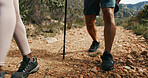 People, legs and hiking with stick on mountain trail for fitness, outdoor exercise or adventure. Hiker, shoes or group of friends walking on dirt road, track or path for trekking expedition in nature
