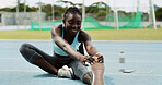 Fitness, black woman and stretching legs on race track for health, wellness or exercise preparation. Sport, happy athlete and runner warm up muscle at stadium for practice or flexibility outdoor