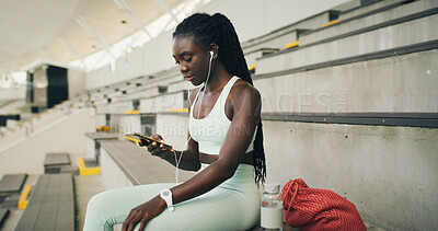 Buy stock photo Earphones, fitness and black woman with cellphone on break with music, playlist or radio for workout. Audio tech, sports and African athlete listening to album on stairs for exercise or training.