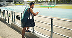 Athlete, man and reading with phone at stadium for social media, fitness app and event agenda. Male person, rest and mobile for texting contact, sports progress results and information for tournament