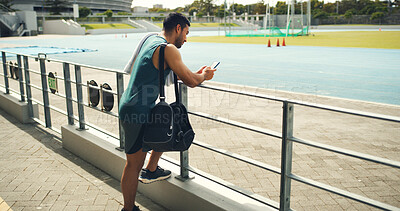 Buy stock photo Athlete, man and reading with phone at stadium for social media, fitness app and event agenda. Male person, rest and mobile for texting contact, sports progress results and information for tournament