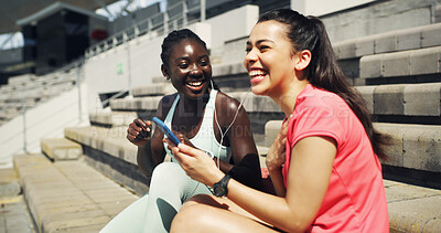Buy stock photo Fitness, earphones and girl friends outdoor with phone for listening to music, networking or social media. Laughing, sports and female athletes on break streaming playlist on mobile app on stairs.