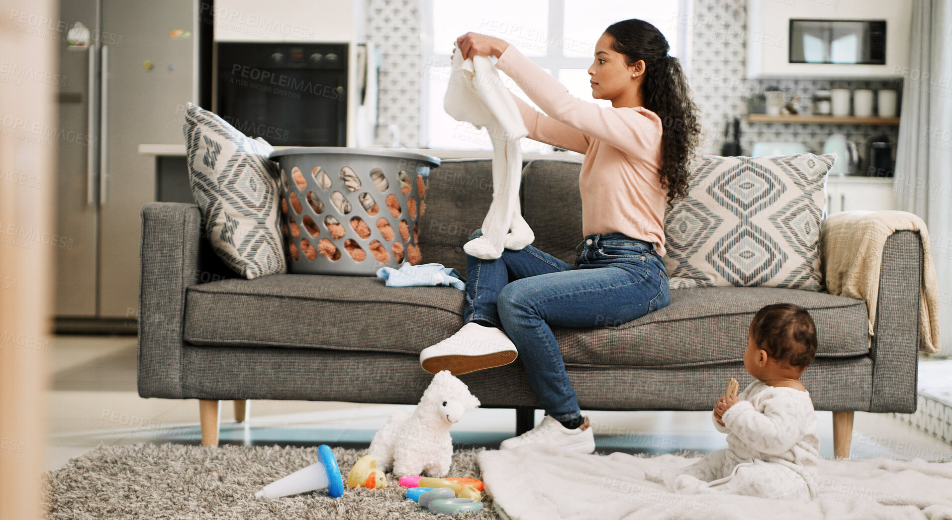 Buy stock photo Mother, folding baby clothes and couch in home, care and domestic chores in lounge with basket. People, mom and laundry with infant on floor, playing and organizing in living room at family house