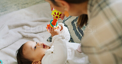Buy stock photo Hands, baby and play with rattle in nursery, mother and stimulation with color, sound and happy in home. People, mom and infant child with toys, game or bonding on bed for development in family house